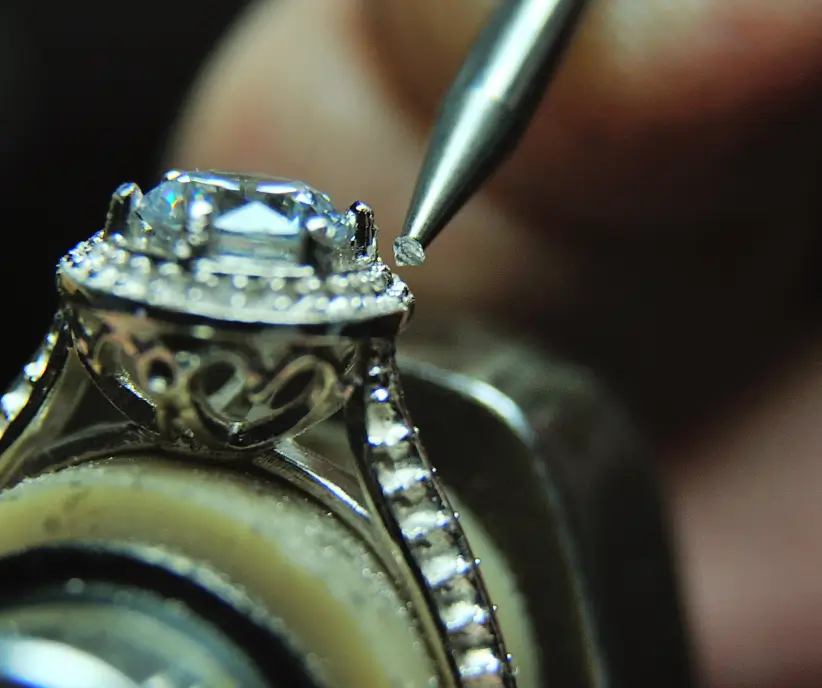 An ornate ring set with a large pale blue stone, held under the light