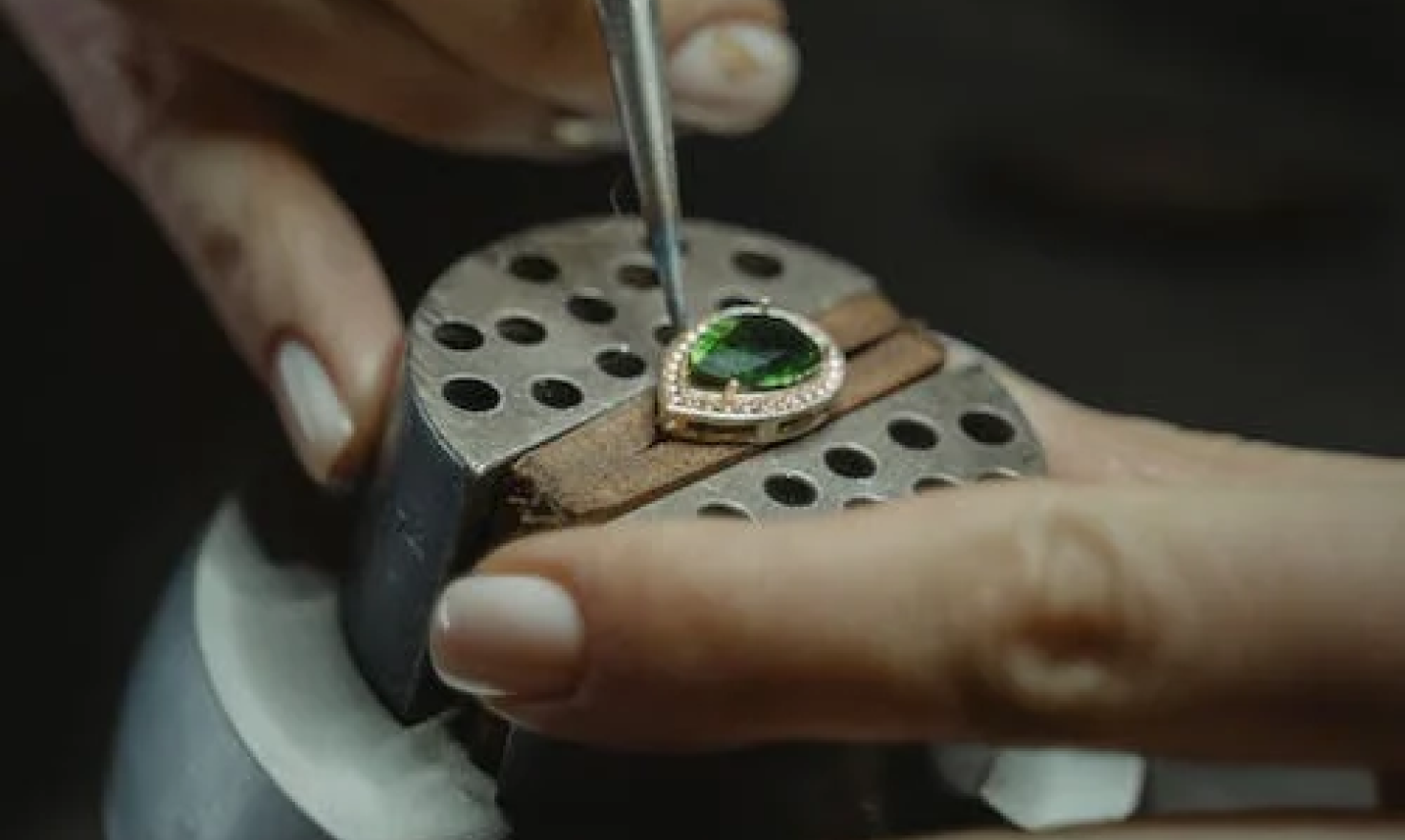 A jeweler setting an emerald into a gold ring at the bench