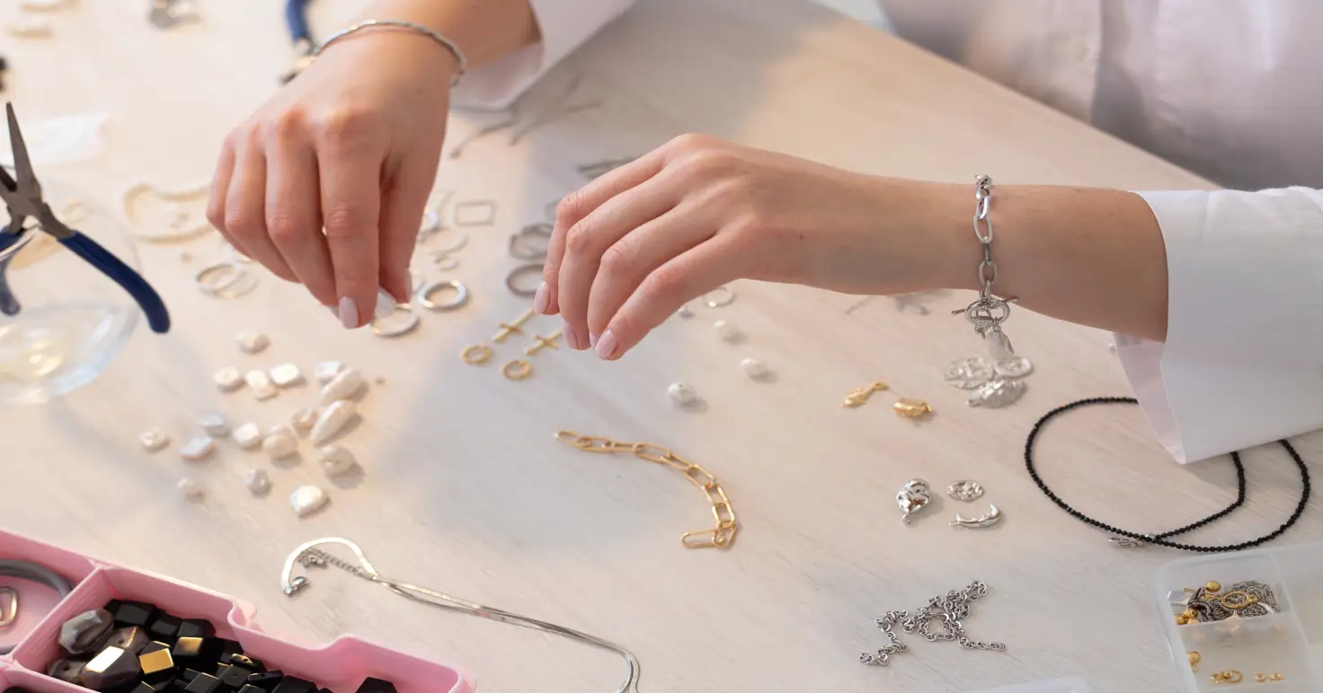 Hands laying out gold chains and findings across a workbench