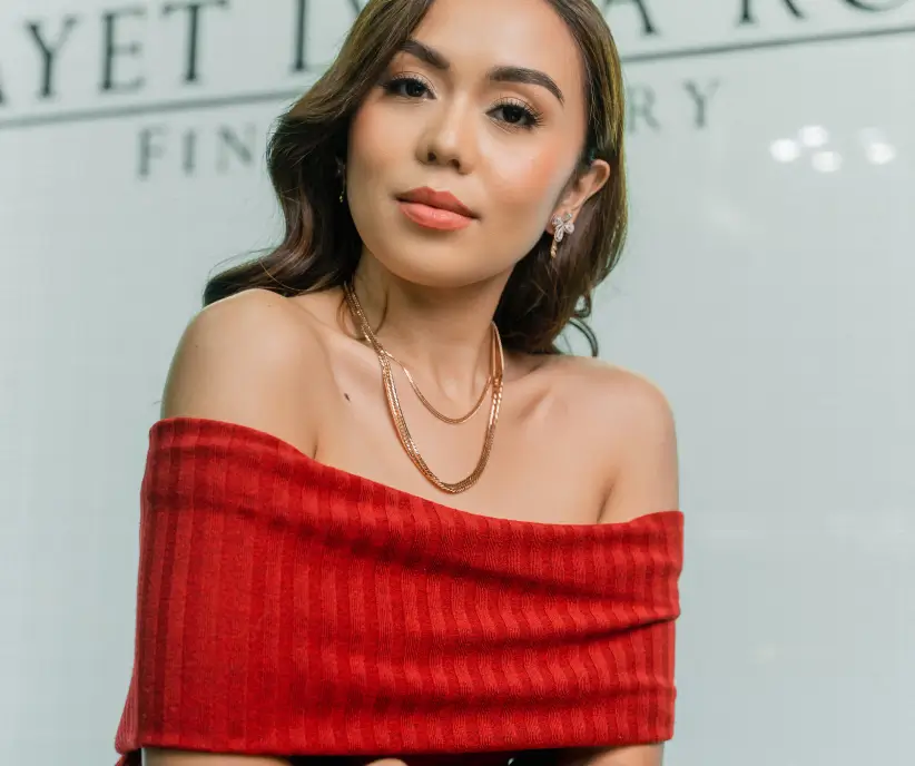 Mayet De La Rosa wearing a layered gold necklace before the house wordmark